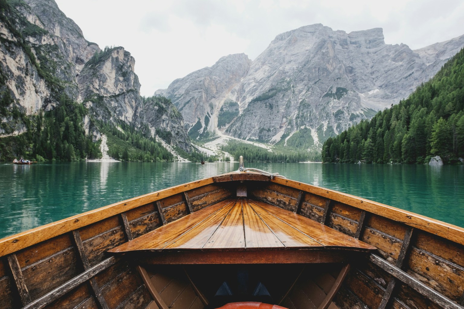 a wooden boat in a body of water with a mountain in the background